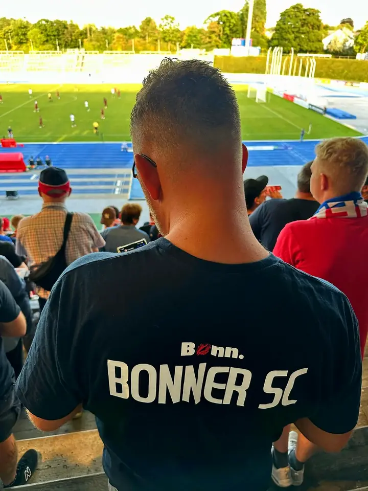 Sascha Frenz verfolgt im Bonner-SC-Shirt ein Spiel im Stadion.