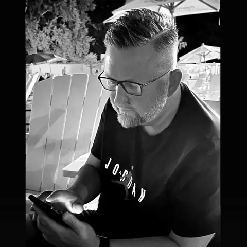 Sascha Frenz schaut in einem ruhigen Schwarz-Weiß-Moment auf sein Smartphone